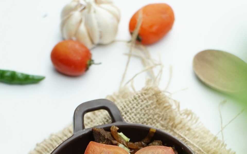 Hearty meat stew with tomato and herbs in a bowl.