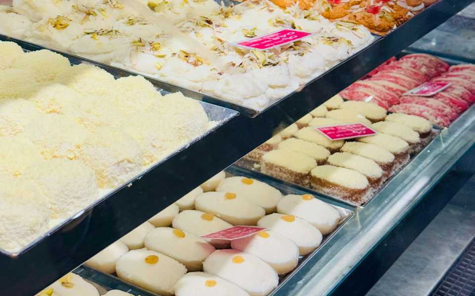 Assorted colorful Indian sweets in a shop-style display.