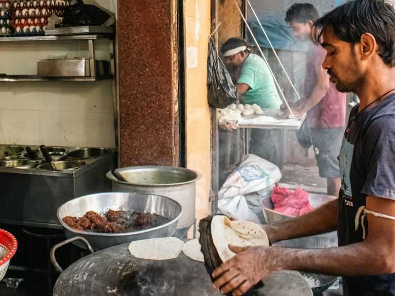 Cook preparing Indian flatbread on a large hot griddle.